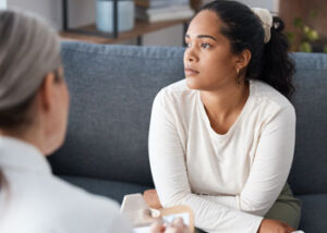 Woman sighs while talking to counselor in anxiety treatment program 